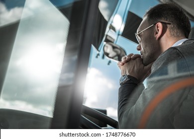 Confused And Pensive Bus Coach Driver Behind Vehicle Wheel Thinking About The Future Of His Transportation Business.