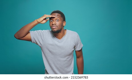 Confused Person Using Hand Over Forehead To Look Around, Searching For Clue In Distance. Young Adult Looking Forward, Having Interest In Exploration And Feeling Pensive, Confident Man With Curiosity.