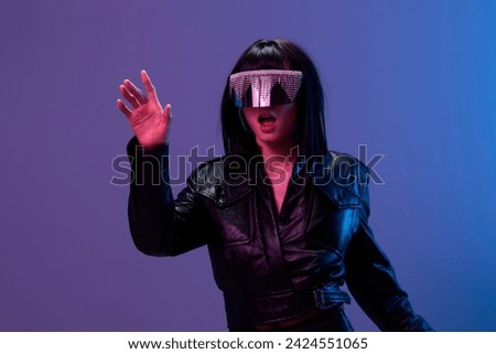 Confused pretty awesome brunet lady in leather jacket trendy specular sunglasses touch invisible object posing isolated in blue violet color light background. Neon party Cyberpunk concept. Copy space