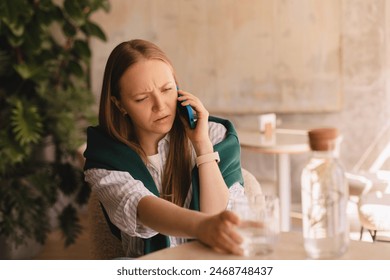 Confused puzzled blonde woman in casual clothes, sits in cafe, holds a smartphone in her hand, look questioningly, calling by mobile phone. Girl getting surprising bad news, straight hand to water. - Powered by Shutterstock