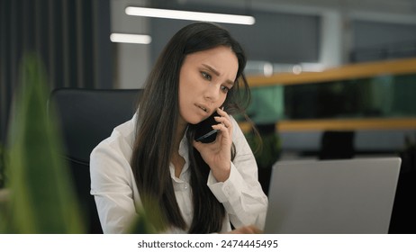 Confused puzzled serious businesswoman girl office worker corporate manager business woman talking mobile phone listening bad news typing laptop multitasking problem consult client call computer using - Powered by Shutterstock