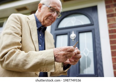 Confused Senior Man With Early Stage Dementia Trying To Find Correct Door Key Outside House