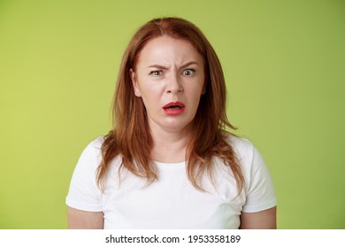 Confused shocked gasping middle-aged redhead woman cringe frustrated puzzled open mouth speechless freak out strange shocking scene stand green background perplexed disappointed - Shutterstock ID 1953358189