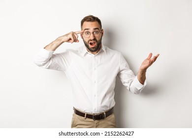 Confused And Shocked Man Pointing At Head, Scolding Employee For Acting Stupid, Standing Over White Background