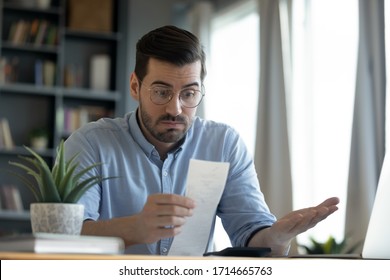 Confused shocked man wearing glasses looking at receipt, checking domestic bills, unhappy businessman anxious about bankruptcy, financial problem, bank debt, high taxes or lack of money