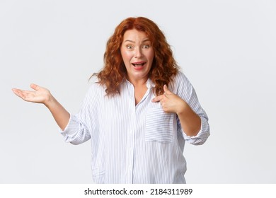 Confused And Surprised Middle-aged Woman React To Nonsense Accusations, Pointing At Herself And Raise Hand Sideways Clueless, Standing Puzzled Over White Background