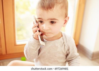 Confused Toddler With Phone In His Hand. Juvenile Justice Concept
