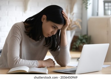 Confused unhappy young korean asian woman looking at laptop screen, feeling dissatisfied reading email with bad news, stuck with difficult working task, thinking of problem solution at home office.
