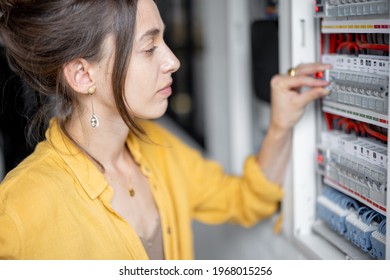 Confused Woman Having Problems With Electricity At Home, Speaks On The Phone Trying To Solve The Problem. Concept Of Female Incompetence In Home Electricity