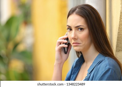 Confused Woman Looking At Camera Talking On Phone In A Colorful Street