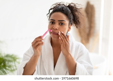 Confused Woman Shaving Natural Moustaches Removing Facial Upper Lip Hair With Safety Razor Standing In Modern Bathroom Indoors, Looking At Camera. Depilation And Hair Removal Concept