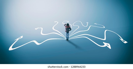 Confused woman stands in front of different arrows . The concept of hard choices. - Shutterstock ID 1288964233