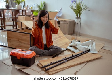 Confused Woman While Assembling New Furniture At Home