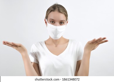 Confused Young Girl Shrugging Shoulders, Making Helpless Gesture With Hands, Throws Up Her Hands In Confusion Wearing Face Mask On The White Background In The Studio