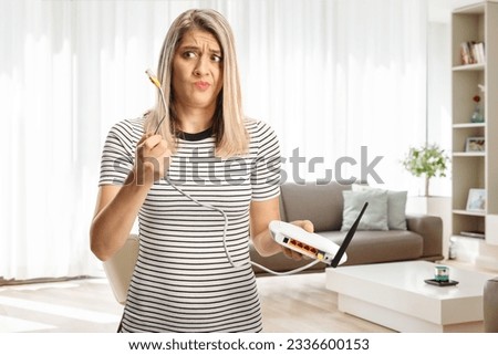 Confused young woman holding a router in a living room