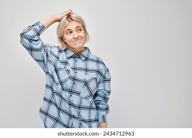 Confused young woman scratching head, wearing plaid shirt, isolated on grey background. - Powered by Shutterstock