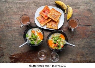 Congee With Minced Pork And Slices Of Bread And Delicious Strawberry Jam Is A Favorite Breakfast For Thai People. On Wood Table Texture. Top View