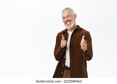 Congrats, Well Done. Smiling Handsome Senior Man, Mature Male Model Pointing Fingers At Camera, Congratulating, Praising And Complimenting, Standing Over White Background.