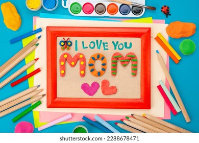 Congratulations from a child on Mother's Day. Bright hand drawn childish card with crafted plasticine colorful mom lettering, butterfly. Flat lay children's creative handmade multicolor Modeling Clay - Powered by Shutterstock