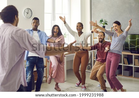 Congratulations: Diverse group of excited young people meet man who's achieved great success. Long time no see: Happy, emotional friends spread arms wide open to hug friend who's finally back home