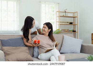 Congratulations. Loving asian mature daughter surprised mother with present in Mother's Day, giving her handmade card and gift box - Powered by Shutterstock