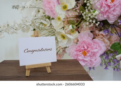 Congratulations text write on paper card with wooden easel and flowers decoration on wooden background
