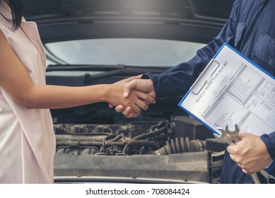 Congratulations. Young Businesswoman Shaking Hands With Mechanic The Car Dealer In Auto Show After A Successful Deal.