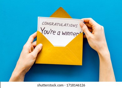 Congratulations You're a winner. Hands holding envelope with letter. Blue background top view