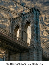 conic Brooklyn Bridge captured from dynamic angles, highlighting its suspension cables, stone towers, and bustling pedestrian paths. Sunrise glows, twilight hues, views of Manhattan and the East River