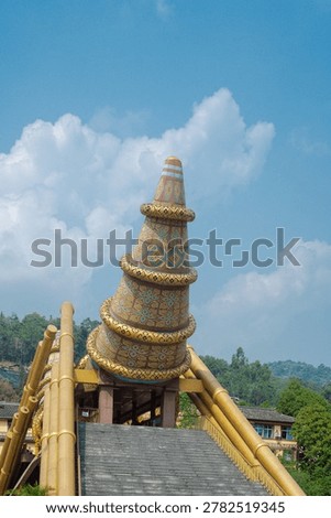 Conical tower ascent features patterned structure supported by gold beams above stone steps leading toward Pingbian cultural complex. Crisp textures, saturated motifs, gentle atmospheric, Yunnan. CN