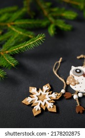 Coniferous branches in background. Wooden snowflake and owl on dark table top view. Vertical photo for advertising Christmas concept. copy space