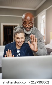 Connect To Loved Ones Wherever You Are. Shot Of A Senior Couple Waving While Using A Laptop At Home.