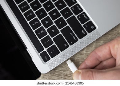 Connect the usb type-c cable to the computer. Connecting the usb type-c cable to the charging connector close-up. A man connects usb type-c cable to a laptop connector. High quality photo