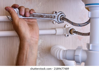 Connecting faucet to water supply using flexible braided hoses, plumber tightens nut with wrench.