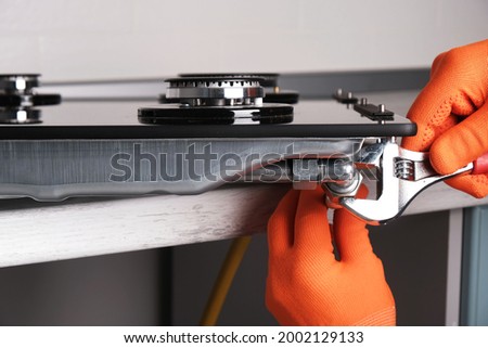 Connecting  gas hose to  hob, hands with an adjustable wrench close-up