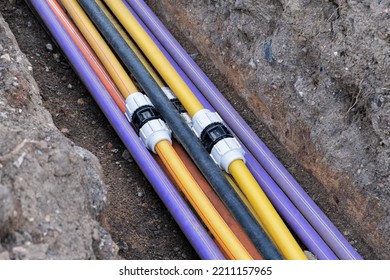 Connecting Underground Electric Cable Infrastructure Installation. Construction Site With A Lot Of Communication Cables Protected In Tubes. High Speed Internet Network Cables Are Buried 