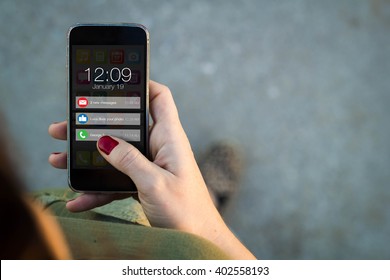 connectivity concept: Top view of woman walking in the street using her mobile phone with notifications on screen. All screen graphics are made up.