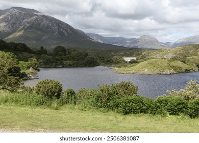 Connemara's stunning summer landscape features a serene lake surrounded by lush greenery and rugged mountains, reflecting clear blue skies and offering a peaceful, picturesque view of Ireland's natura - Powered by Shutterstock