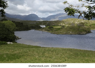 Connemara's stunning summer landscape features a serene lake surrounded by lush greenery and rugged mountains, reflecting clear blue skies and offering a peaceful, picturesque view of Ireland's natura - Powered by Shutterstock