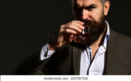 Connoisseur With Beard And Bourbon Or Whiskey On Black Background. Drinking And Party Concept. Man With Serious Face Holding Glass Of Alcohol. Businessman Ready To Drink Cognac Or Brandy.