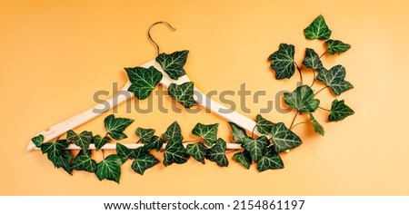 Conscious and environmentally friendly consupmtion in shopping.Recycling or zero waste concept.Shopping,sale,promo concept.Hangers entwined with plants on yellow background with copy space.