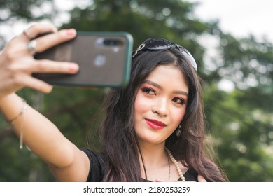 A Conscious And Vain Young Woman Tries Stretches Her Arm For A Selfie. Taking A Nice Photo Compulsively While At The Park. A Narcissist With Selfitis.