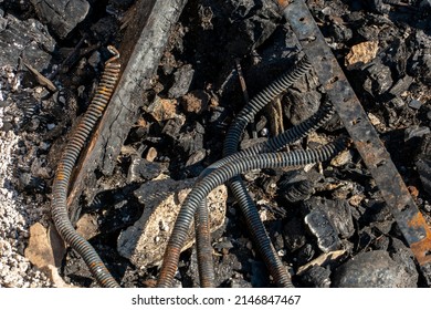 The Consequences Of A Fire In An Old Wooden Country House. Ashes And Burnt Boards Close-up. A Fire In A Residential Wooden House Due To Arson Of Dry Grass.