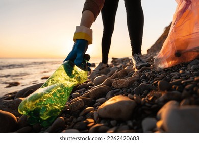 Conservation of ecology and garbage collection for recycling. A volunteer collects plastic bottles by the sea. Concept of coastal cleanup and global environmental pollution. - Powered by Shutterstock