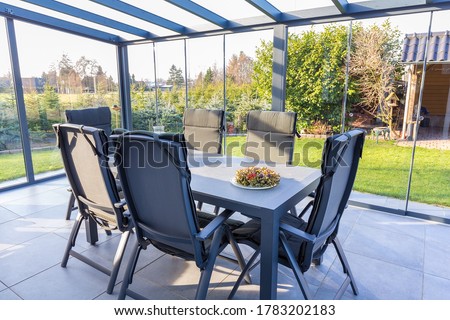 Conservatory of glass with table and chairs in garden