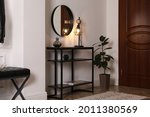Console table with decor and mirror on white wall in hallway. Interior design