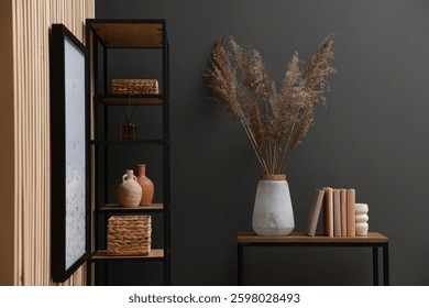 Console table with decor and shelving unit near grey wall in room. Interior design