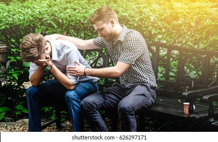 Consoling friend. Frustrated young man in shirt and tie being consoled by his friend in garden - Powered by Shutterstock