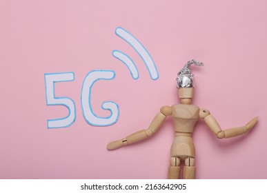 Conspiracy Theory. Wooden Puppet In Foil Hat And Word 5G On Pink Background