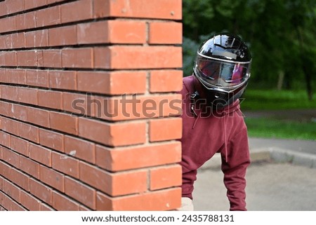 Conspiracy using a motorcycle helmet - a guy is watching someone, looking out from behind the wall